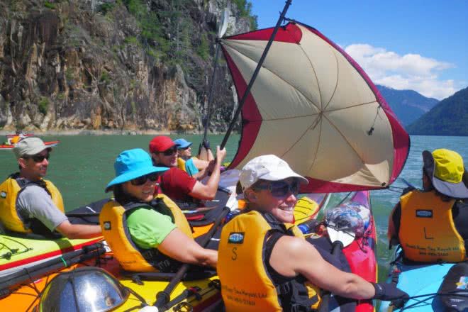 Guests set up a sail to catch the wind on a Guided Kayak Tour