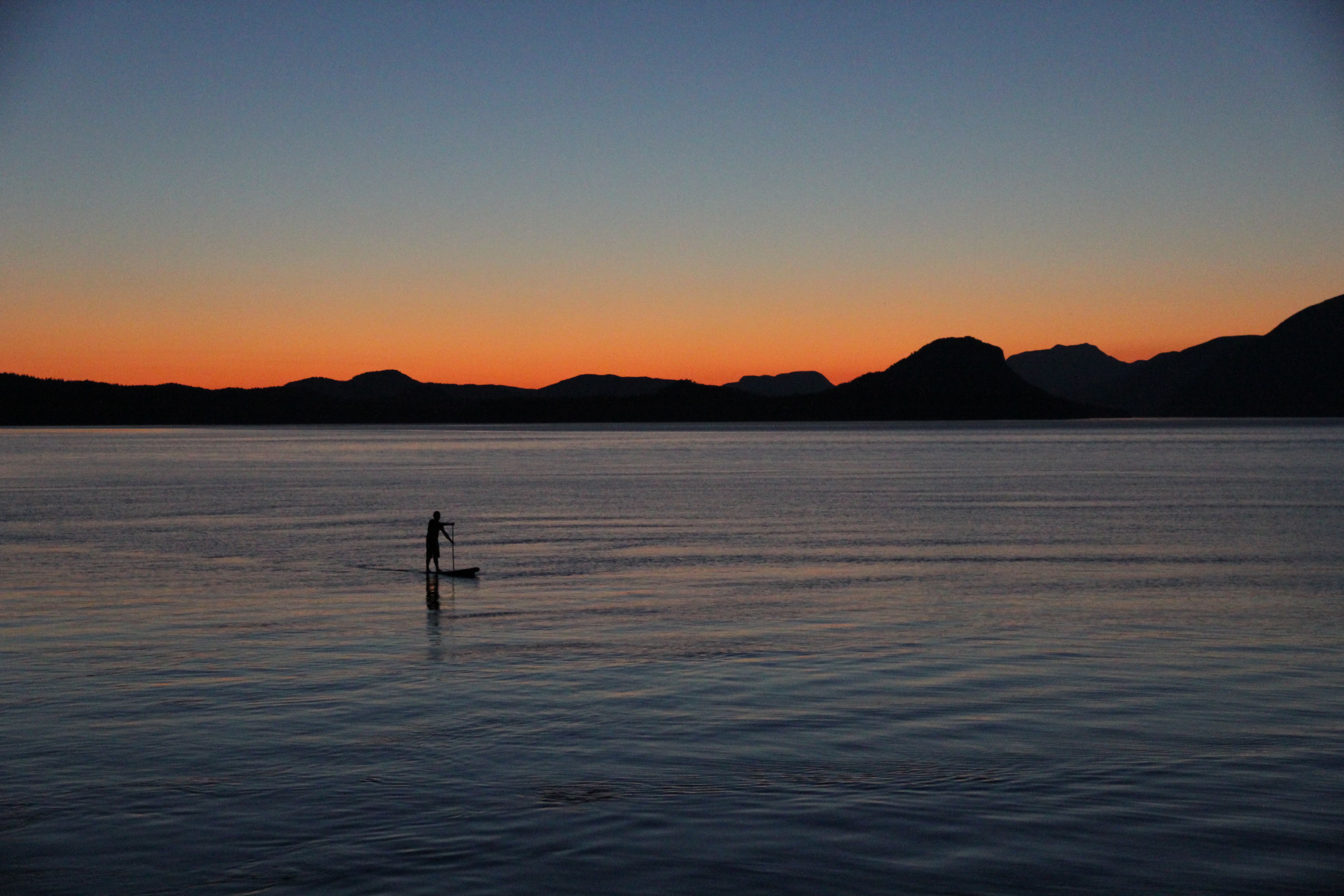 A guest paddle boarding as the sun sets on coastal British Columbia