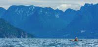 A kayaker looks up at the imposing Coast Mountains in Desolation Sound