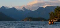 Two kayakers paddling in Desolation Sound with Mount Denman in the distance