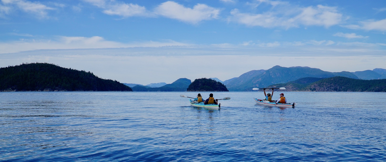 Two double kayakers and four guests paddling towards Kinghorn Island in Desolation Sound